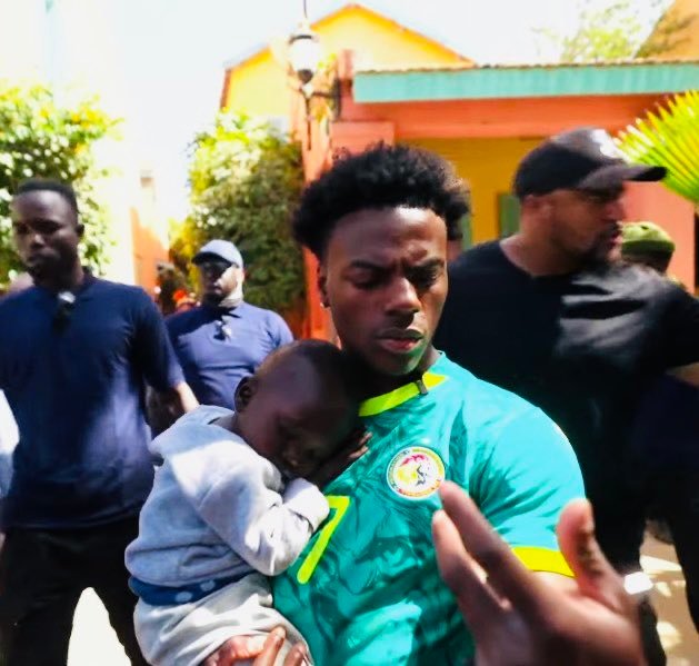 IShowSpeed prend un enfant sénégalais dans ses bras lors de sa tournée Speed Does Africa, moment d'émotion et de sourire.