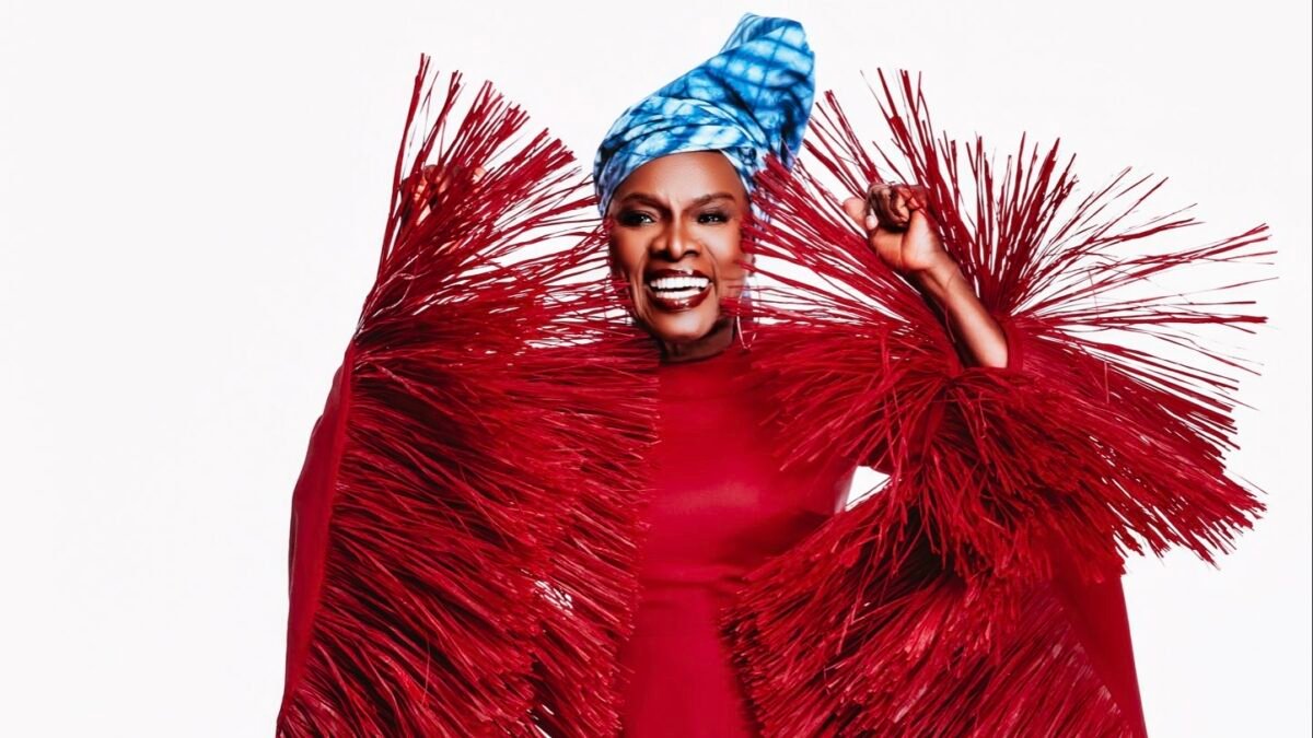Angélique Kidjo souriante, en tenue rouge, portrait éditorial