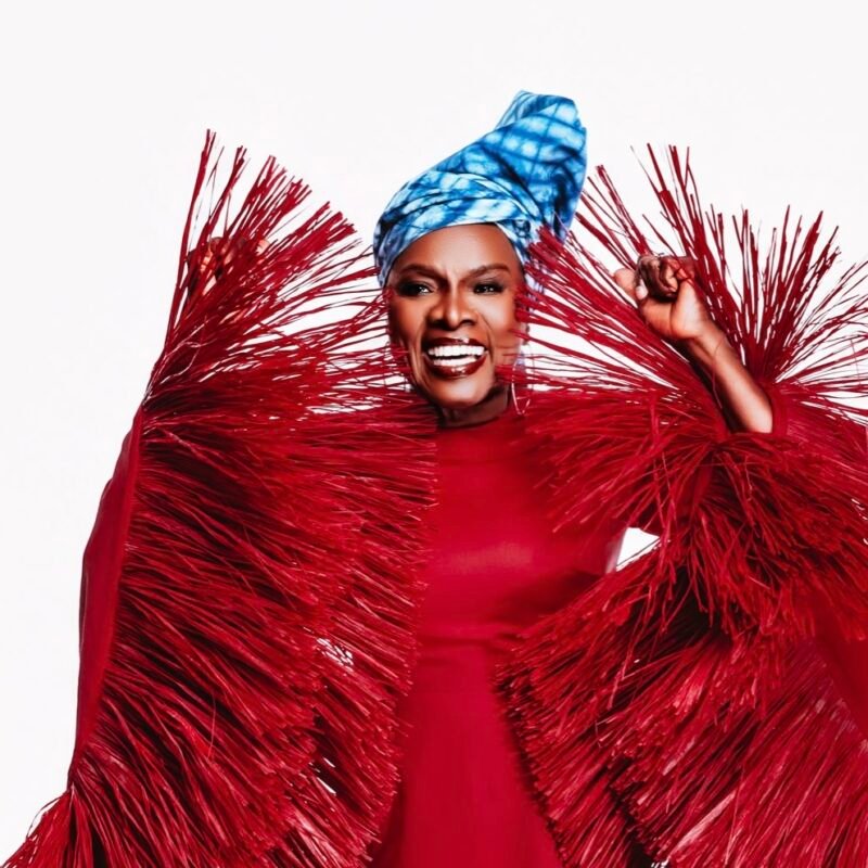 Angélique Kidjo souriante, en tenue rouge, portrait éditorial