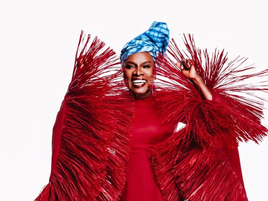 Angélique Kidjo souriante, en tenue rouge, portrait éditorial